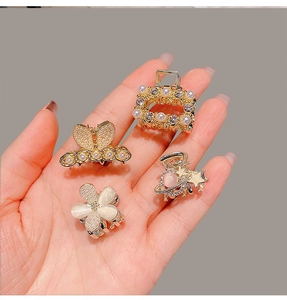 Close-up of four mini gold alloy hair claws featuring bow, flower, and star designs with pearls
