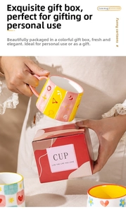 Detail of creative ceramic mug with pink heart-shaped handle and striped gift box