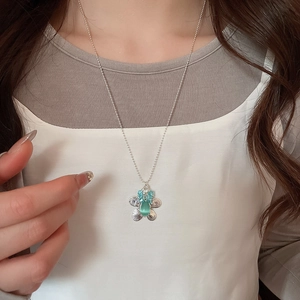 Close-up of floral silver necklace with turquoise gemstone on a model's neck