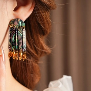 Detail of bohemian drop earrings with colorful shell texture on a model wearing them