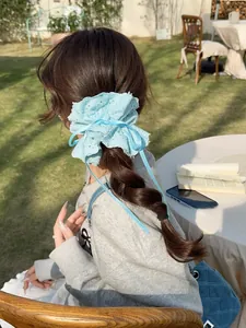 Detail of light blue lace scrunchie with long ribbon streamers worn on a ponytail