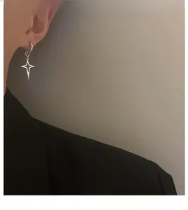 Orecchini a stella d'argento minimalisti indossati che mostrano uno stile moderno