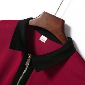 Detail des burgunderfarbenen Golfpolos mit Reißverschluss und Etikett aus Polyester