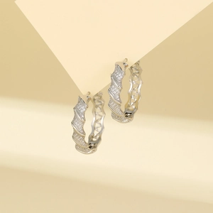 Detailed view of silver hoop earrings featuring wave design and pavé set cubic zirconia