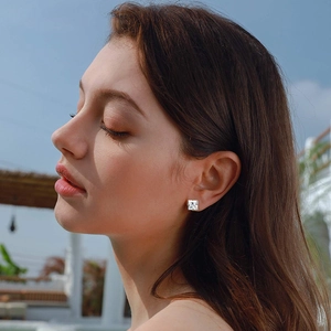Classic silver square zircon stud earrings with four-prong setting worn by a model outdoors