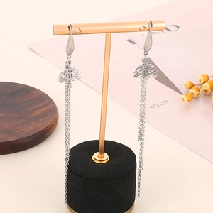 Detail view of silver tree of life earrings with long chain tassels on a gold stand