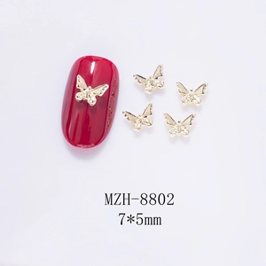 Macro shot of 7x5mm mini golden metal butterfly nail charms on a deep red nail