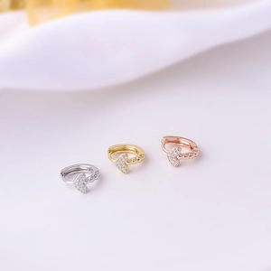 Close-up of three dainty hoop earrings in silver, gold, and rose gold with heart pendants