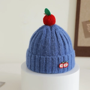 Detailed knit texture of children's navy blue beanie with apple embroidery and pom-pom
