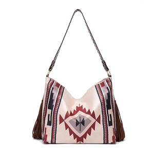 Close-up of bohemian woven shoulder bag with ethnic geometric patterns and brown fringes