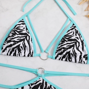Sexy zebra print bikini set with sky blue trim and metal ring details on marble surface