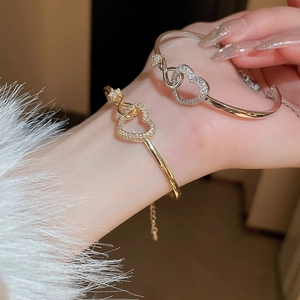 Close-up of gold and silver heart-shaped bracelets with zircon pavé on a female wrist