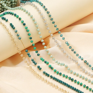Faceted green and blue crystal bead necklaces with stainless steel chains on soft fabric