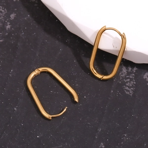 Detailed view of long oval huggie earrings in 18k gold-plated finish on stone surface
