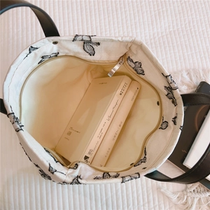 Détail du sac cabas en toile avec broderie papillon et fermeture à glissière sécurisée