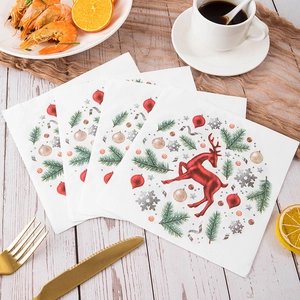 Christmas dinner napkins with red reindeer and tree prints on a festive wooden table