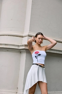 Close-up of white crop top featuring a red rose print and irregular skirt detail