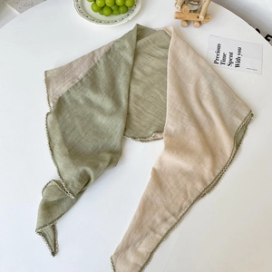 Minimalist green and beige linen scarf with delicate lace trim on a white table