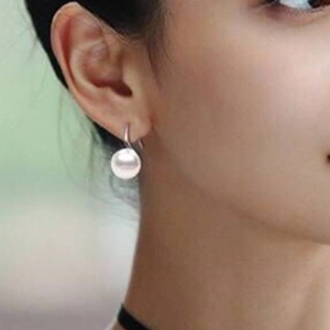 Elegant white natural pearl drop earrings in S925 silver on a female model outdoors