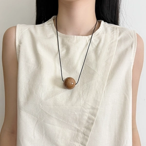 Minimalist long necklace with smooth brown geometric bead pendant on a slim black cord