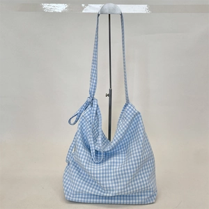 Detail of blue and white gingham canvas bag with unique knot decoration on shoulder strap