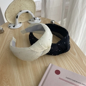 Detailed view of two wide knotted headbands in black and cream with tiny rhinestone accents