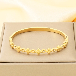 Macro detail of a gold cross bracelet with white rhinestones on smooth satin fabric