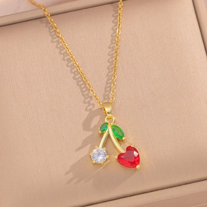 Golden cherry necklace with heart-shaped red stone and green leaf in a jewelry box