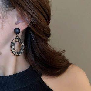 Gros plan de boucles d'oreilles géométriques léopard avec clous noirs sur modèle