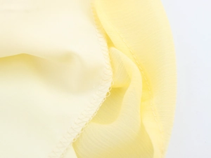 Détail macro du tissu en mousseline jaune clair avec des coutures de bordure soignées