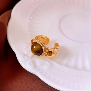 Dettaglio di un anello dorato con occhio di tigre su un piatto di porcellana bianca