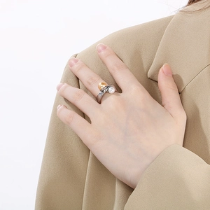 Detail of twisted silver ring with gold and white pearls worn on a khaki blazer