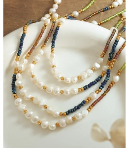 Detail of layered bohemian necklace with freshwater pearls and colorful glass beads on ceramic