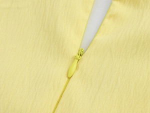 Dettaglio dell'abito giallo operato con cerniera invisibile e trama del tessuto