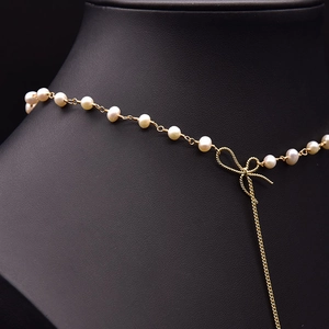 Elegant pearl necklace with golden bow clasp displayed on a black neck mannequin