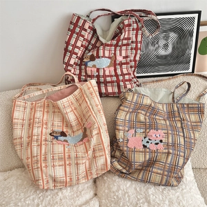 Detail of checkered canvas tote bags with cute animal embroidery on a soft white sofa