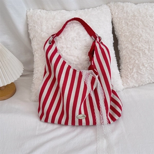 Gros plan du sac cabas en toile rayée rouge avec plaque logo métal et ruban en dentelle