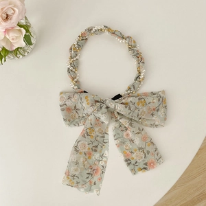Detail of floral fabric headband featuring white pearls and golden chain embellishments