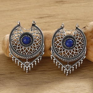 Macro detail of silver vintage bohemian earrings with turquoise stone on wood