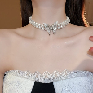 Close-up of double-layer pearl necklace with a silver hollow butterfly pendant on neck