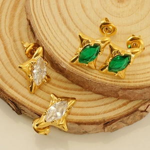 Macro shot of 18k gold plated starburst earrings with emerald and clear zircon inlay