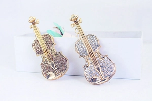 Vue détaillée de deux broches violon dorées avec cristaux brillants sur une boîte