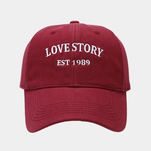Macro detail of the white Love Story embroidery on a burgundy soft cotton baseball cap