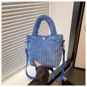 Detail of blue corduroy bucket bag with pleated handle and vertical ribbed texture