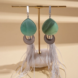Close-up of ethnic style resin earrings with natural feathers on a minimalist display