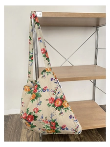 Macro detail of beige floral canvas tote bag featuring vibrant red and yellow flower patterns