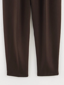 Close-up of dark brown wide-leg trousers showing smooth woven fabric texture and drape