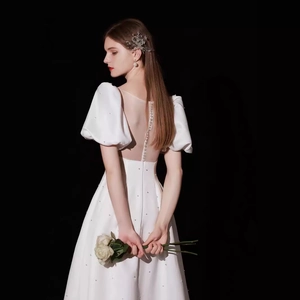Elegant white satin wedding dress with puff sleeves and pearl buttons on sheer back