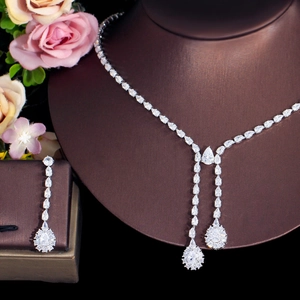 Detail of silver drop necklace and earrings set with sparkling zircons on a dark bust