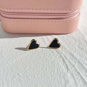 Vue détaillée des boucles d'oreilles cœur avec émail noir et bordure dorée